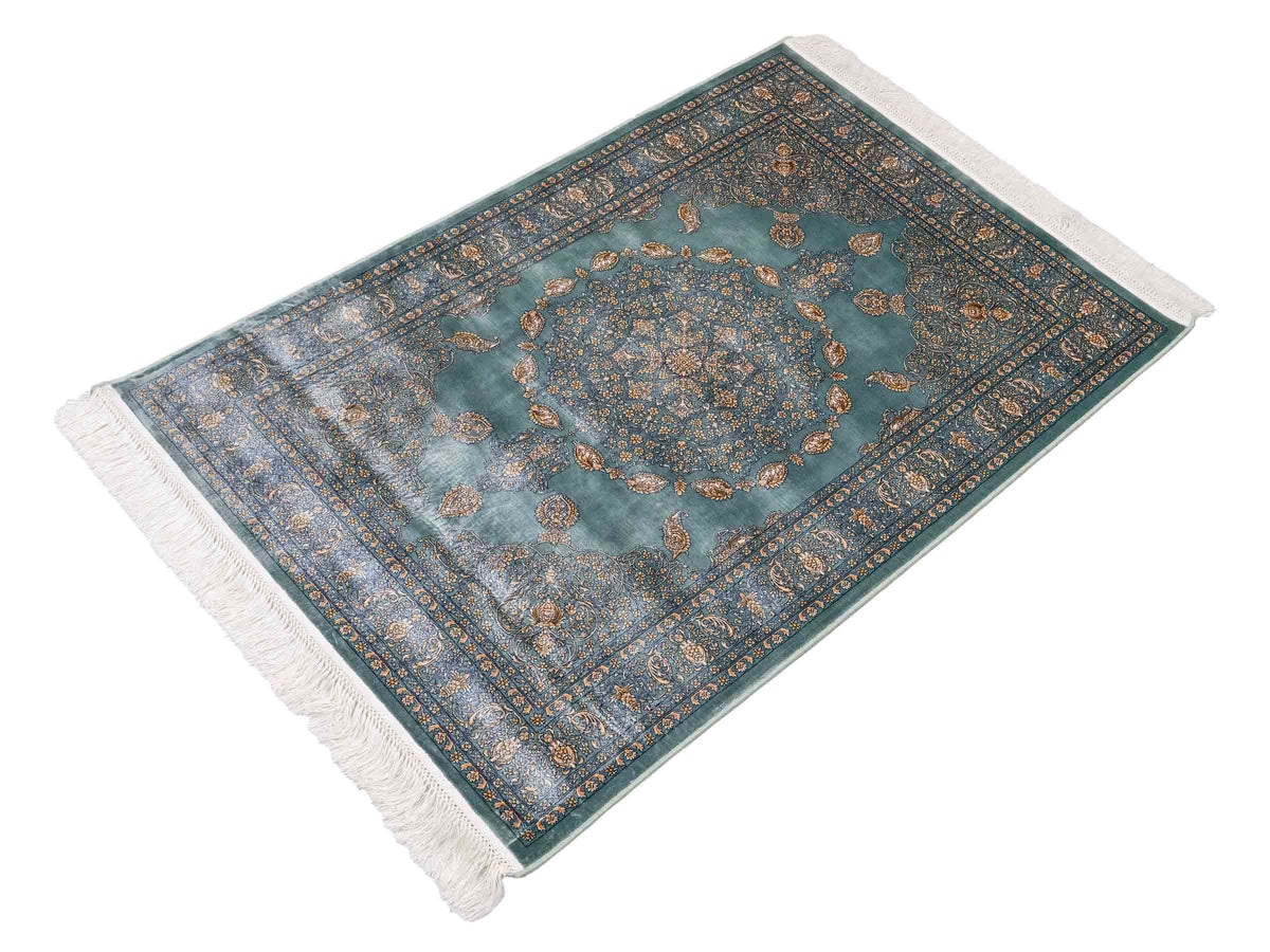 Ghom Maschinenteppich "Anahita" 120 x 80 cm aus pflanzlicher Seide (Viskose) mit Medaillon, Türkis-Gold. Teppichnummer: V3TE096M. Persian Luxury Collection by Khademi. Made in Iran / Persia – Vertrieb durch JUPITER Intl.