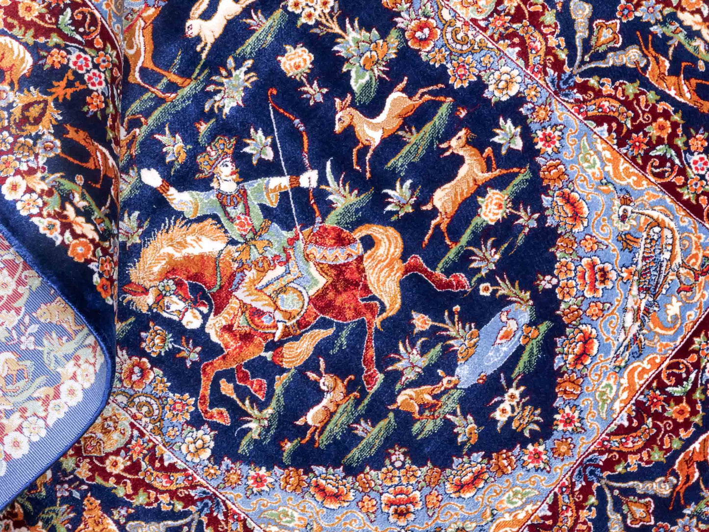 Ghom Maschinenteppich "Banu" 90 x 60 cm aus pflanzlicher Seide (Viskose) mit Jagdmotiv, Marineblau. Teppichnummer: V13NY054H. Persian Luxury Collection by Khademi. Made in Iran / Persia – Vertrieb durch JUPITER Intl.