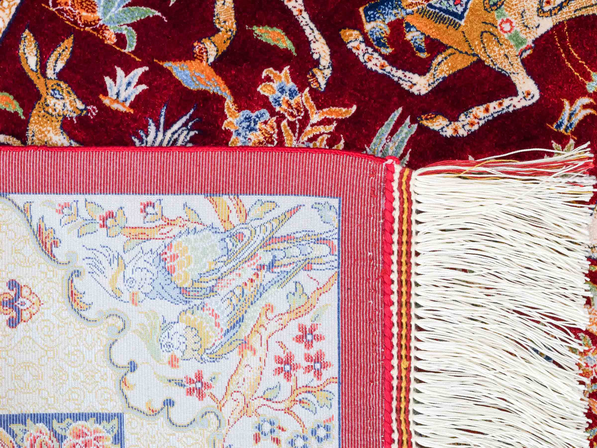 Ghom Maschinenteppich "Fariborz" 90 x 60 cm, mit Jagdmotiv, Rot-Blau, aus pflanzlicher Seide (Viskose), Hand-Finished. Teppichnummer: V25RL054H. Persian Luxury Collection by Khademi. Made in Iran / Persia – Vertrieb durch JUPITER Intl.