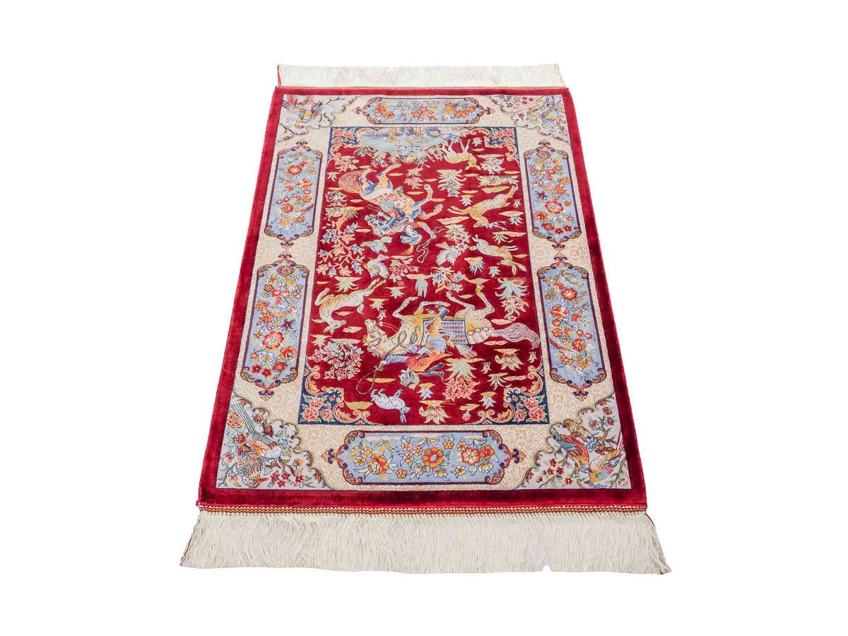 Ghom Maschinenteppich "Fariborz" 90 x 60 cm, mit Jagdmotiv, Rot-Blau, aus pflanzlicher Seide (Viskose), Hand-Finished. Teppichnummer: V25RL054H. Persian Luxury Collection by Khademi. Made in Iran / Persia – Vertrieb durch JUPITER Intl.