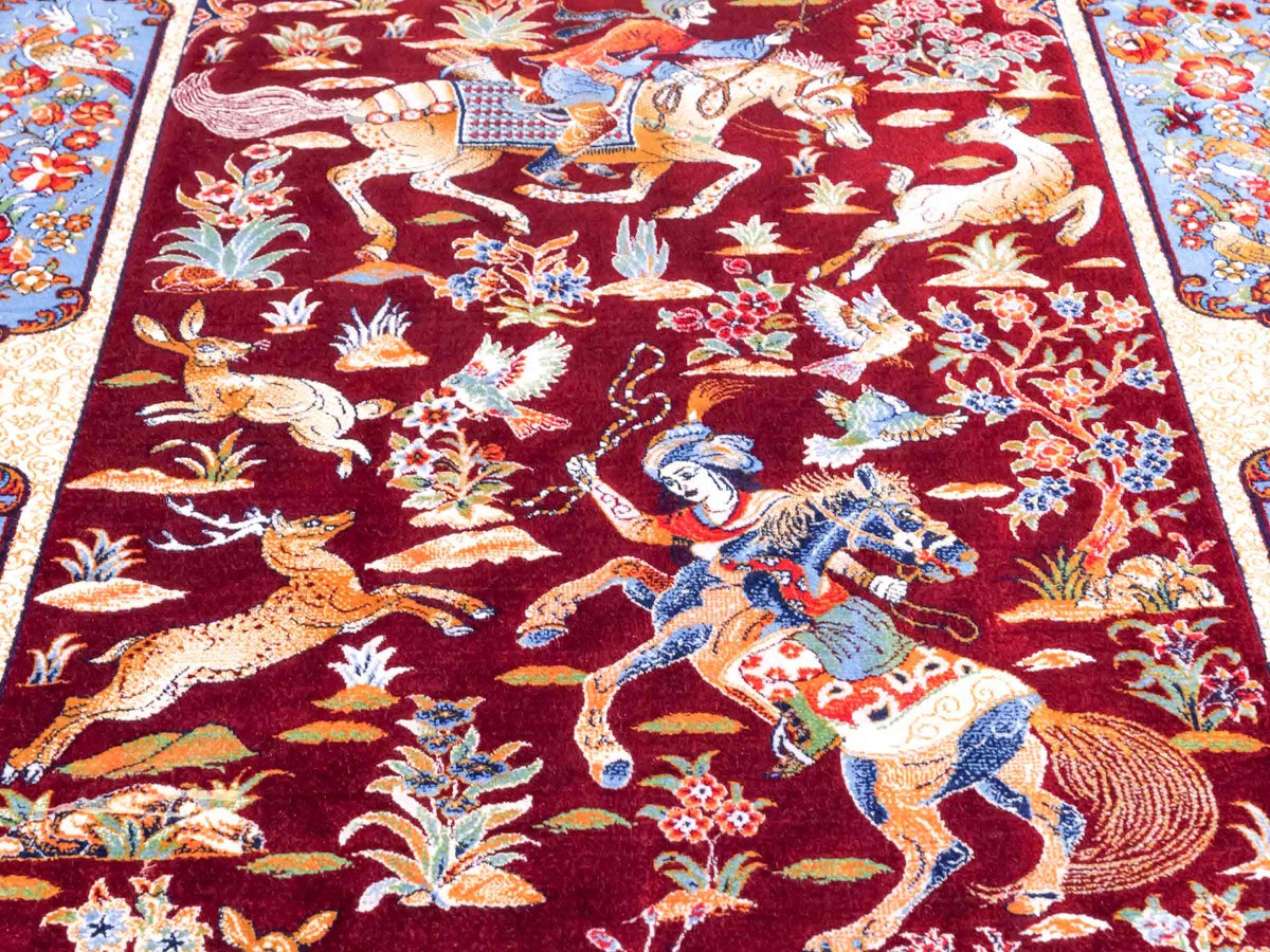 Ghom Maschinenteppich "Fariborz" 90 x 60 cm, mit Jagdmotiv, Rot-Blau, aus pflanzlicher Seide (Viskose), Hand-Finished. Teppichnummer: V25RL054H. Persian Luxury Collection by Khademi. Made in Iran / Persia – Vertrieb durch JUPITER Intl.