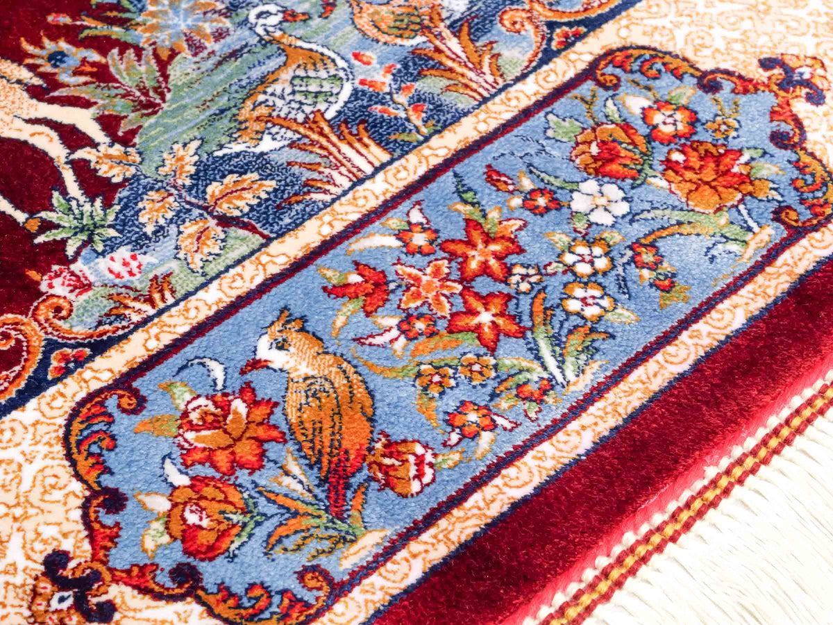 Ghom Maschinenteppich "Fariborz" 90 x 60 cm, mit Jagdmotiv, Rot-Blau, aus pflanzlicher Seide (Viskose), Hand-Finished. Teppichnummer: V25RL054H. Persian Luxury Collection by Khademi. Made in Iran / Persia – Vertrieb durch JUPITER Intl.