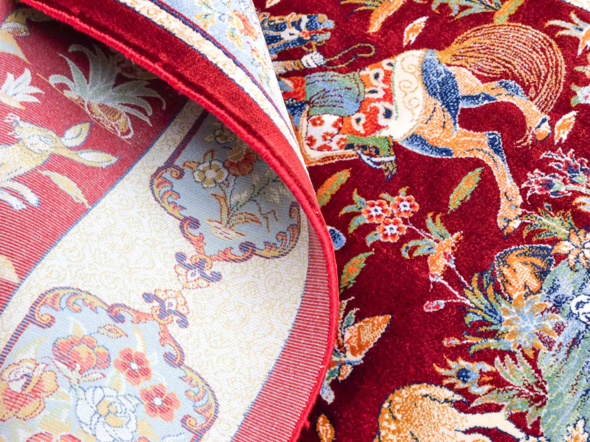 Ghom Maschinenteppich "Fariborz" 90 x 60 cm, mit Jagdmotiv, Rot-Blau, aus pflanzlicher Seide (Viskose), Hand-Finished. Teppichnummer: V25RL054H. Persian Luxury Collection by Khademi. Made in Iran / Persia – Vertrieb durch JUPITER Intl.