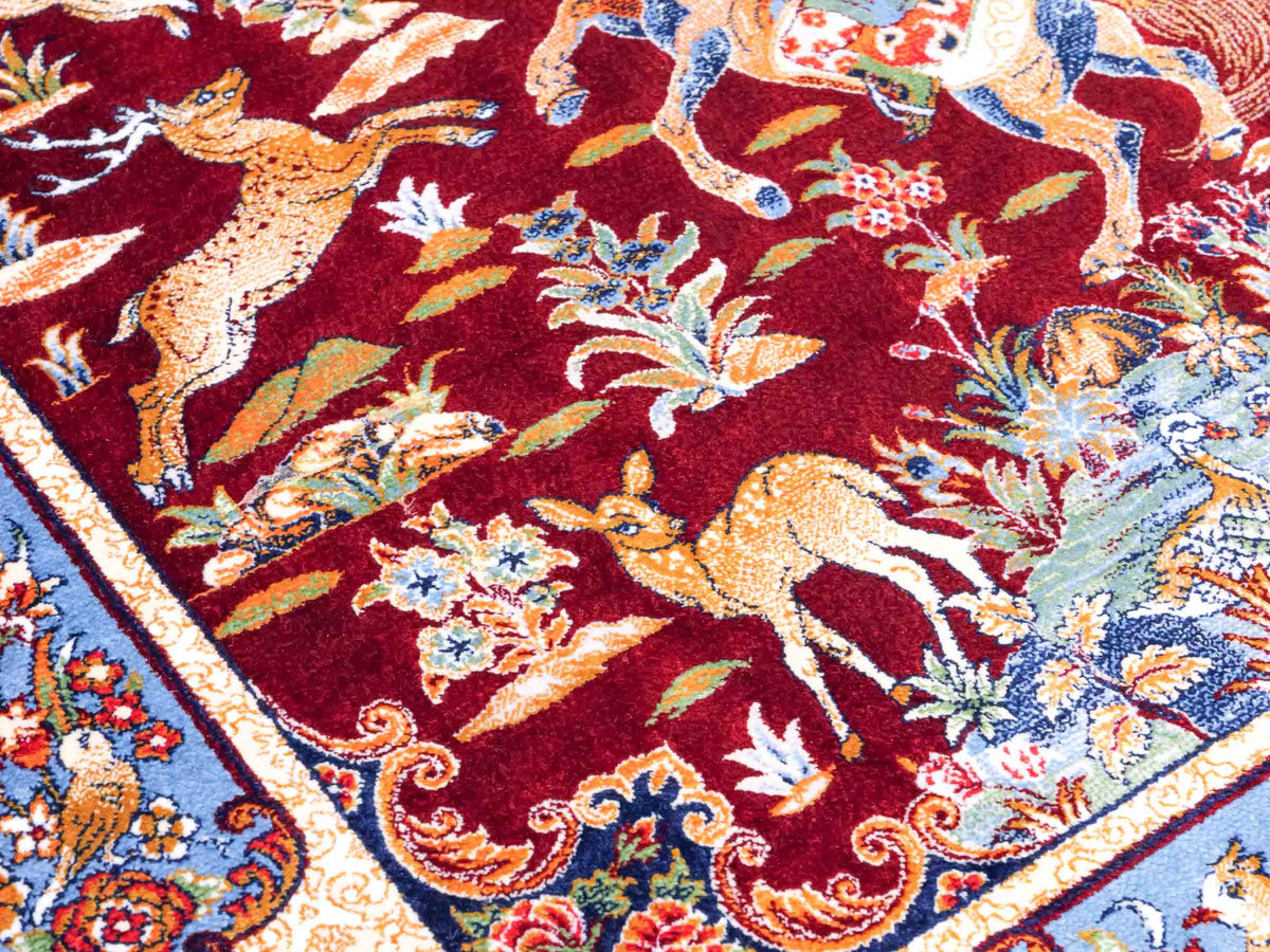 Ghom Maschinenteppich "Fariborz" 90 x 60 cm, mit Jagdmotiv, Rot-Blau, aus pflanzlicher Seide (Viskose), Hand-Finished. Teppichnummer: V25RL054H. Persian Luxury Collection by Khademi. Made in Iran / Persia – Vertrieb durch JUPITER Intl.