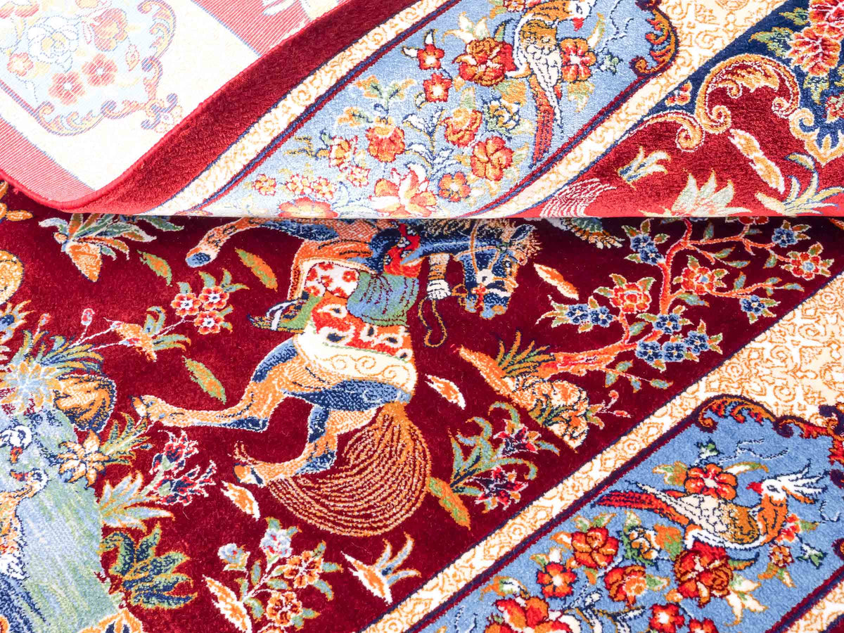 Ghom Maschinenteppich "Fariborz" 90 x 60 cm, mit Jagdmotiv, Rot-Blau, aus pflanzlicher Seide (Viskose), Hand-Finished. Teppichnummer: V25RL054H. Persian Luxury Collection by Khademi. Made in Iran / Persia – Vertrieb durch JUPITER Intl.