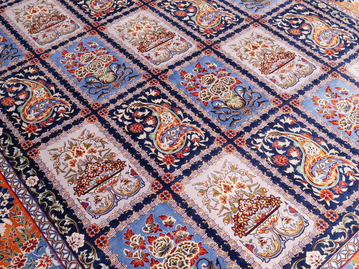 Ghom Maschinenteppich "Ferdowsi" 225 x 150 cm, mit Feldmuster, aus pflanzlicher Seide (Viskose), Marineblau/Mehrfarbig. Teppichnummer: V30NY338H. Persian Luxury Collection by Khademi. Made in Iran / Persia – Vertrieb durch JUPITER Intl.