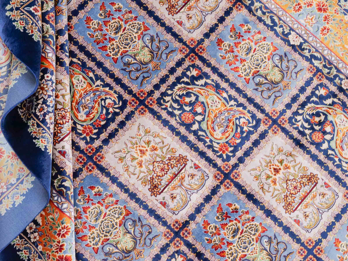 Ghom Maschinenteppich "Ferdowsi" 225 x 150 cm, mit Feldmuster, aus pflanzlicher Seide (Viskose), Marineblau/Mehrfarbig. Teppichnummer: V30NY338H. Persian Luxury Collection by Khademi. Made in Iran / Persia – Vertrieb durch JUPITER Intl.