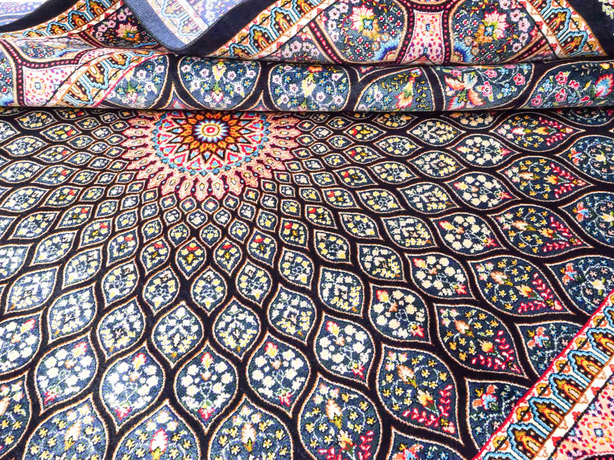 Ghom Maschinenteppich "Goshasp" 150 x 100 cm, mit Medaillon, aus pflanzlicher Seide (Viskose), Schwarz-Grün-Mehrfarbig. Teppichnummer: V40BK150H. Persian Luxury Collection by Khademi. Made in Iran / Persia – Vertrieb durch JUPITER Intl.