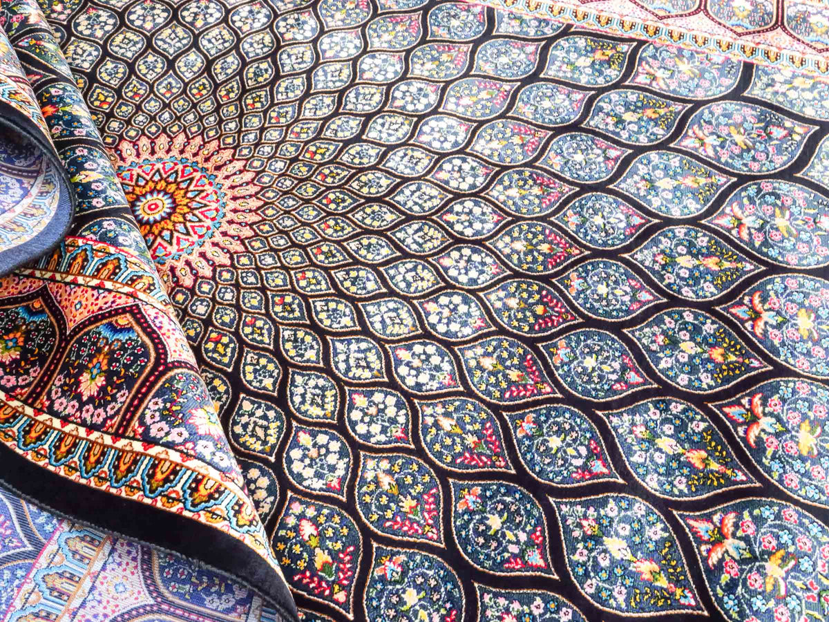 Ghom Maschinenteppich "Goshasp" 150 x 100 cm, mit Medaillon, aus pflanzlicher Seide (Viskose), Schwarz-Grün-Mehrfarbig. Teppichnummer: V40BK150H. Persian Luxury Collection by Khademi. Made in Iran / Persia – Vertrieb durch JUPITER Intl.