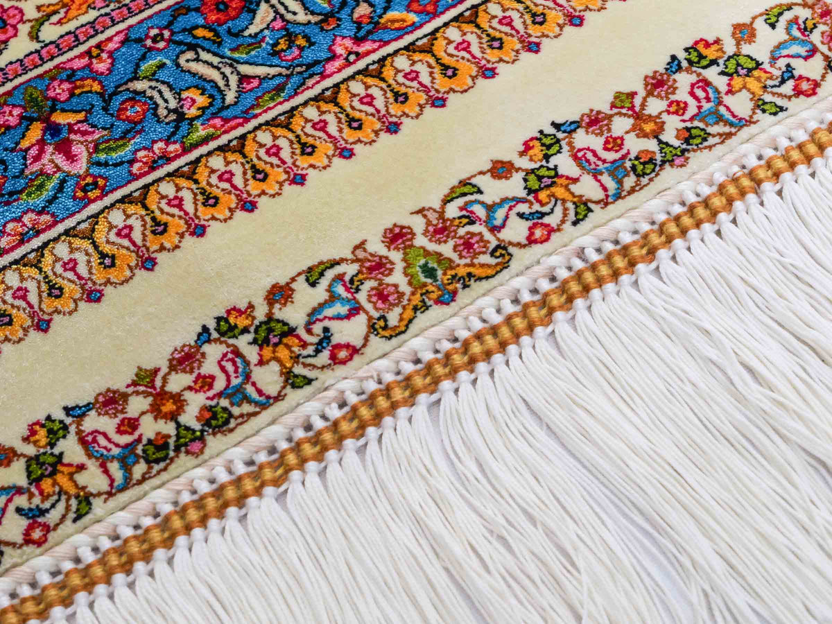 Ghom Maschinenteppich "Homay" 225 x 150 cm, mit Medaillon, aus pflanzlicher Seide (Viskose), Cremeweiß/Hellblau. Teppichnummer: V45CT338H. Persian Luxury Collection by Khademi. Made in Iran / Persia – Vertrieb durch JUPITER Intl.