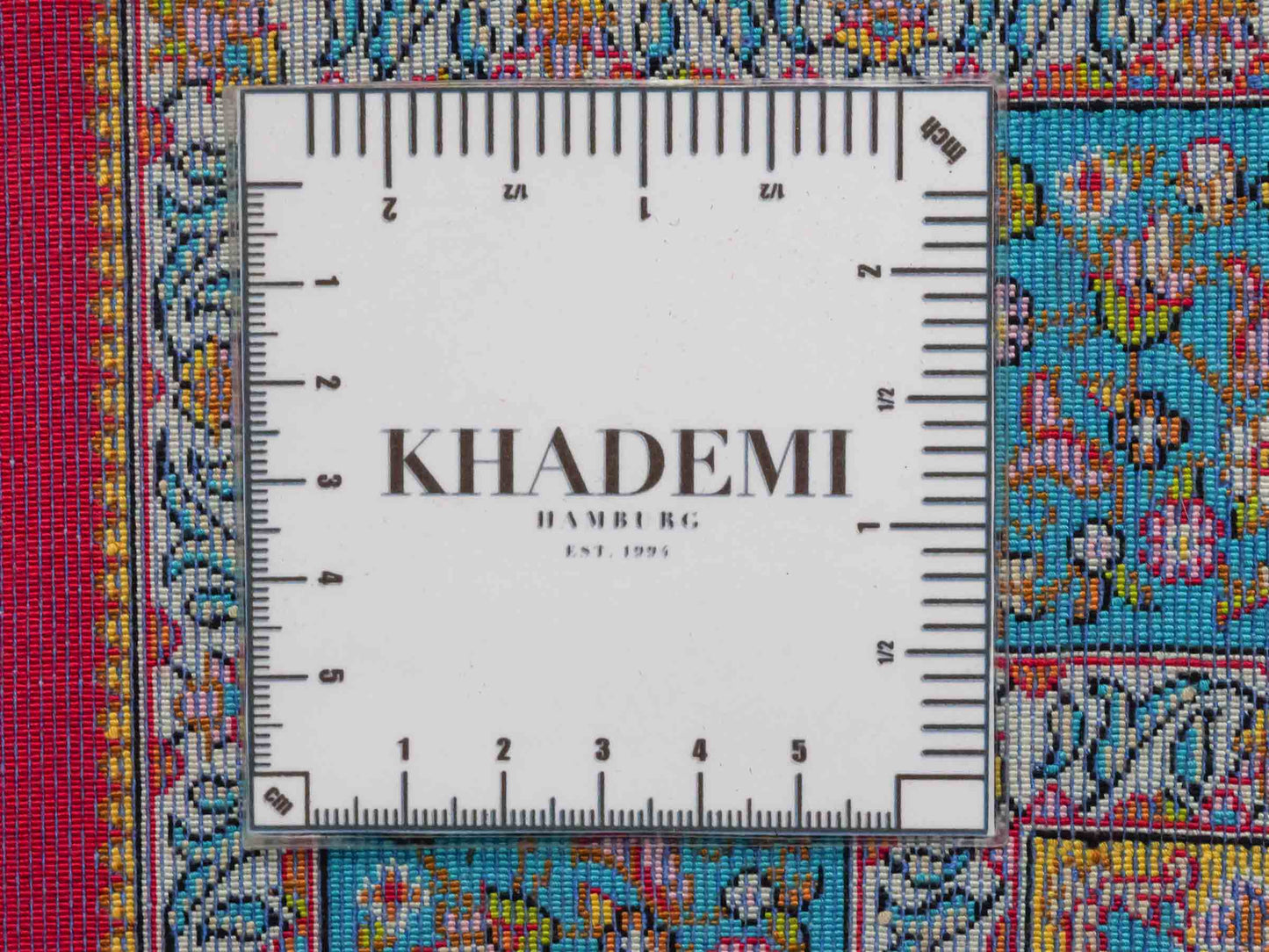Ghom Maschinenteppich "Homay" 90 x 60 cm aus pflanzlicher Seide (Viskose) mit Medaillon, Rot, Hellblau. Teppichnummer: V45RD054H. Persian Luxury Collection by Khademi. Made in Iran / Persia – Vertrieb durch JUPITER Intl.