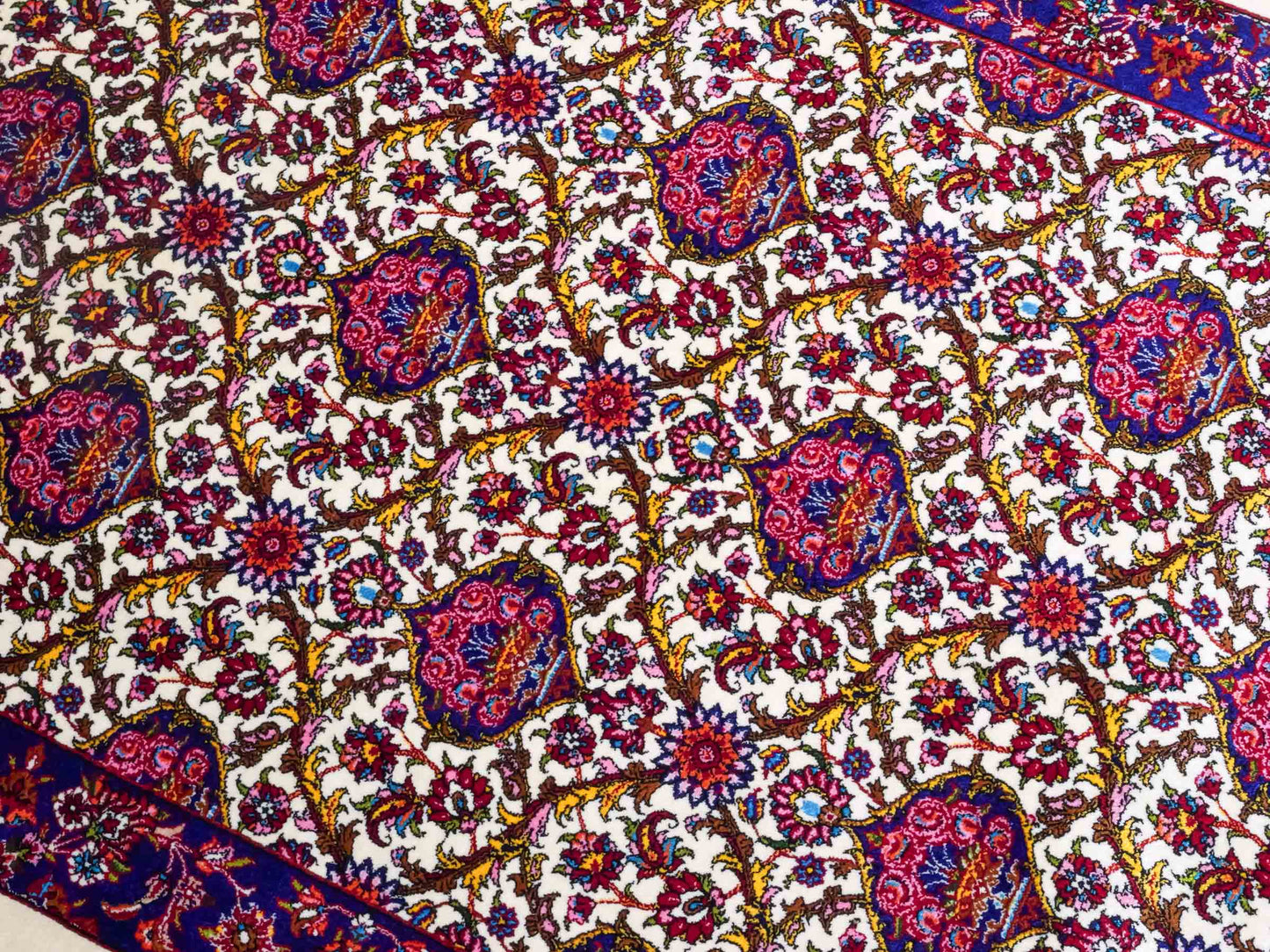 Ghom Maschinenteppich "Kiyumars" 90 x 60 cm aus pflanzlicher Seide (Viskose), Allover-Design, Cremeweiß, Blau, Rot. Teppichnummer: V53CR054M. Persian Luxury Collection by Khademi. Made in Iran / Persia – Vertrieb durch JUPITER Intl.