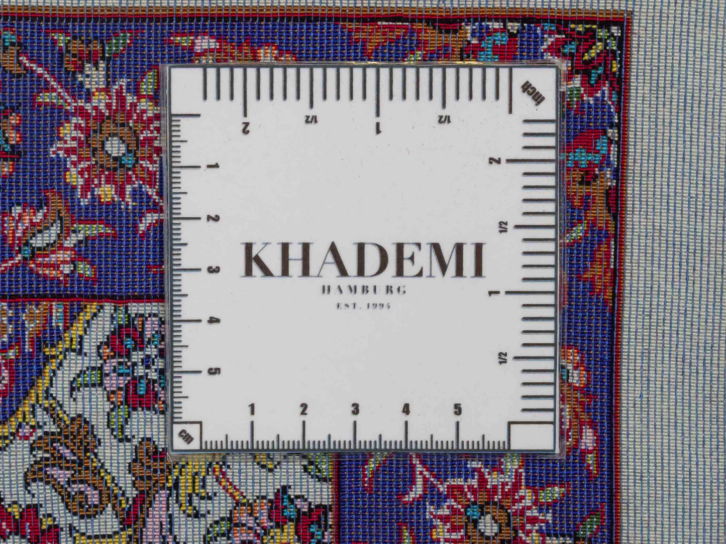 Ghom Maschinenteppich "Kiyumars" 90 x 60 cm aus pflanzlicher Seide (Viskose), Allover-Design, Cremeweiß, Blau, Rot. Teppichnummer: V53CR054M. Persian Luxury Collection by Khademi. Made in Iran / Persia – Vertrieb durch JUPITER Intl.