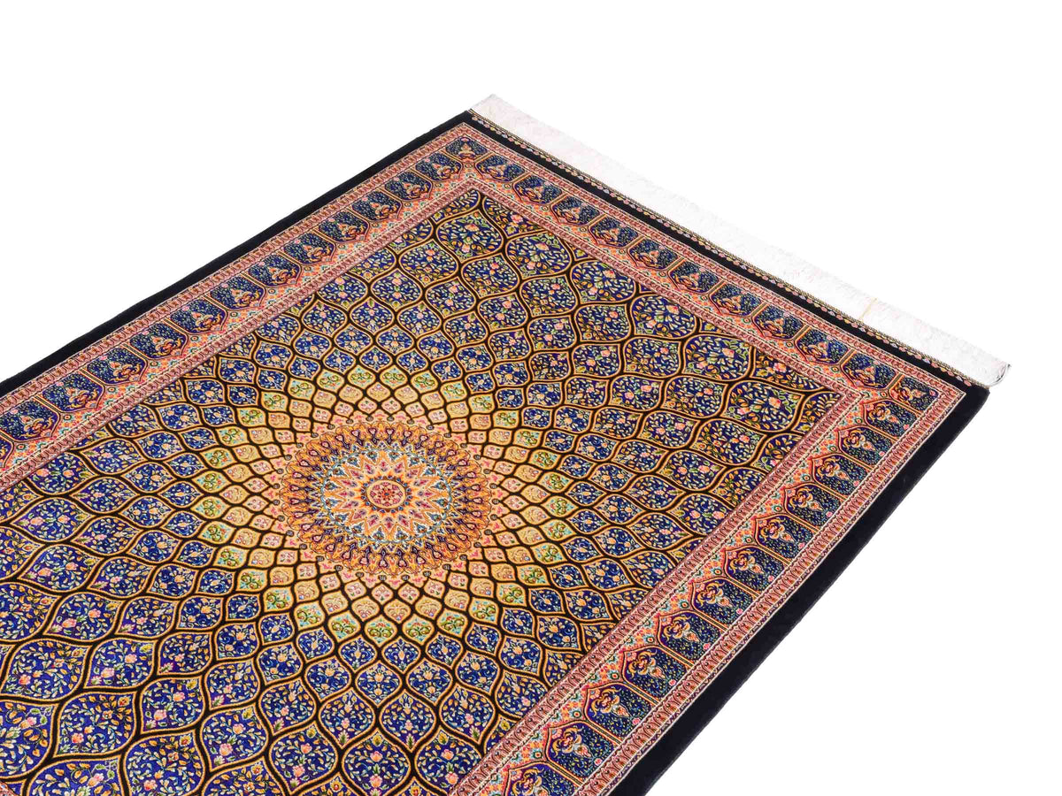 Ghom Maschinenteppich "Manuchehr" 150 x 100 cm, mit Medaillon, aus pflanzlicher Seide (Viskose), Schwarz/Blau/Gold. Teppichnummer: V56BD150H. Persian Luxury Collection by Khademi. Made in Iran / Persia – Vertrieb durch JUPITER Intl.