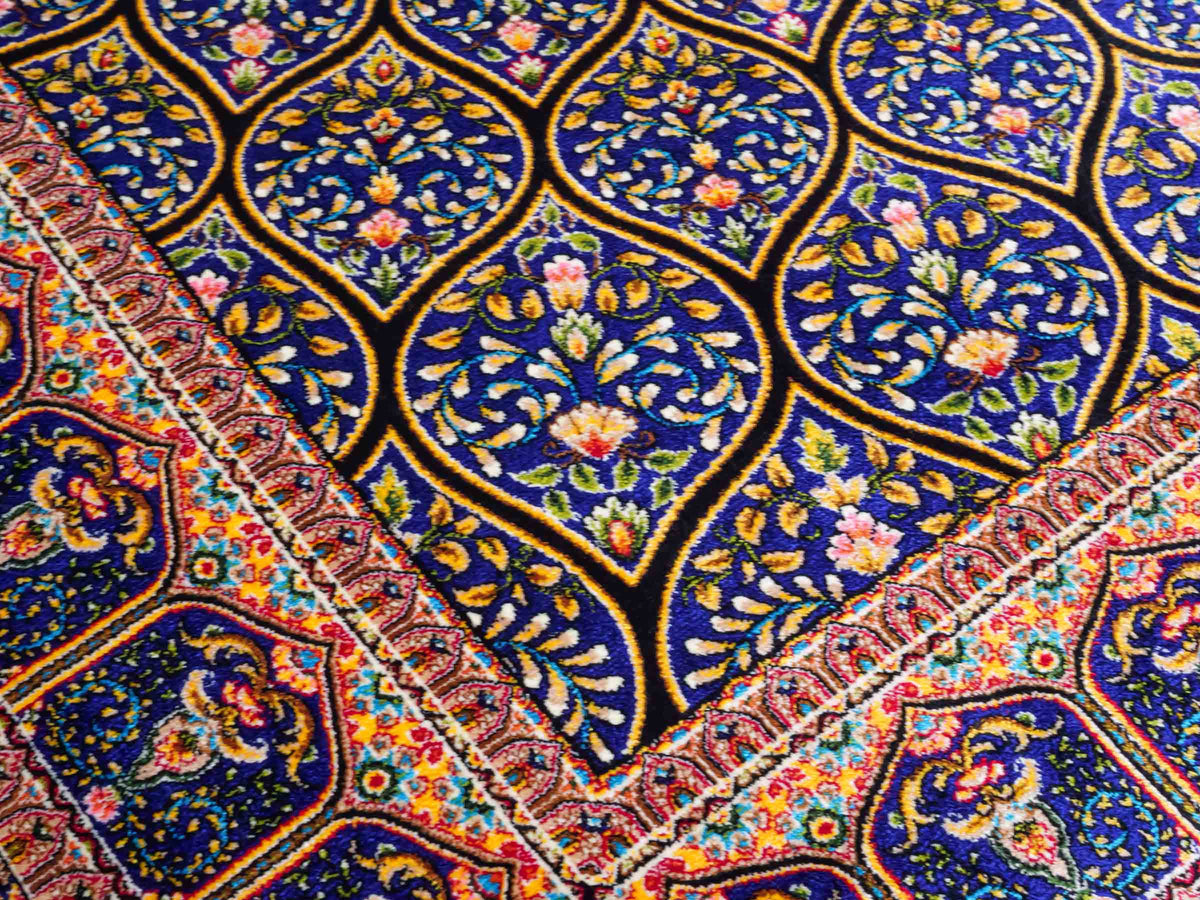 Ghom Maschinenteppich "Manuchehr" 150 x 100 cm, mit Medaillon, aus pflanzlicher Seide (Viskose), Schwarz/Blau/Gold. Teppichnummer: V56BD150H. Persian Luxury Collection by Khademi. Made in Iran / Persia – Vertrieb durch JUPITER Intl.