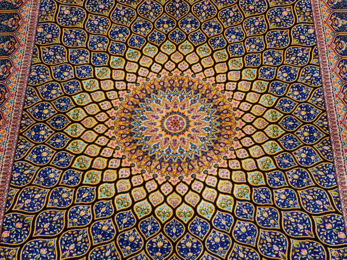 Ghom Maschinenteppich "Manuchehr" 150 x 100 cm, mit Medaillon, aus pflanzlicher Seide (Viskose), Schwarz/Blau/Gold. Teppichnummer: V56BD150H. Persian Luxury Collection by Khademi. Made in Iran / Persia – Vertrieb durch JUPITER Intl.