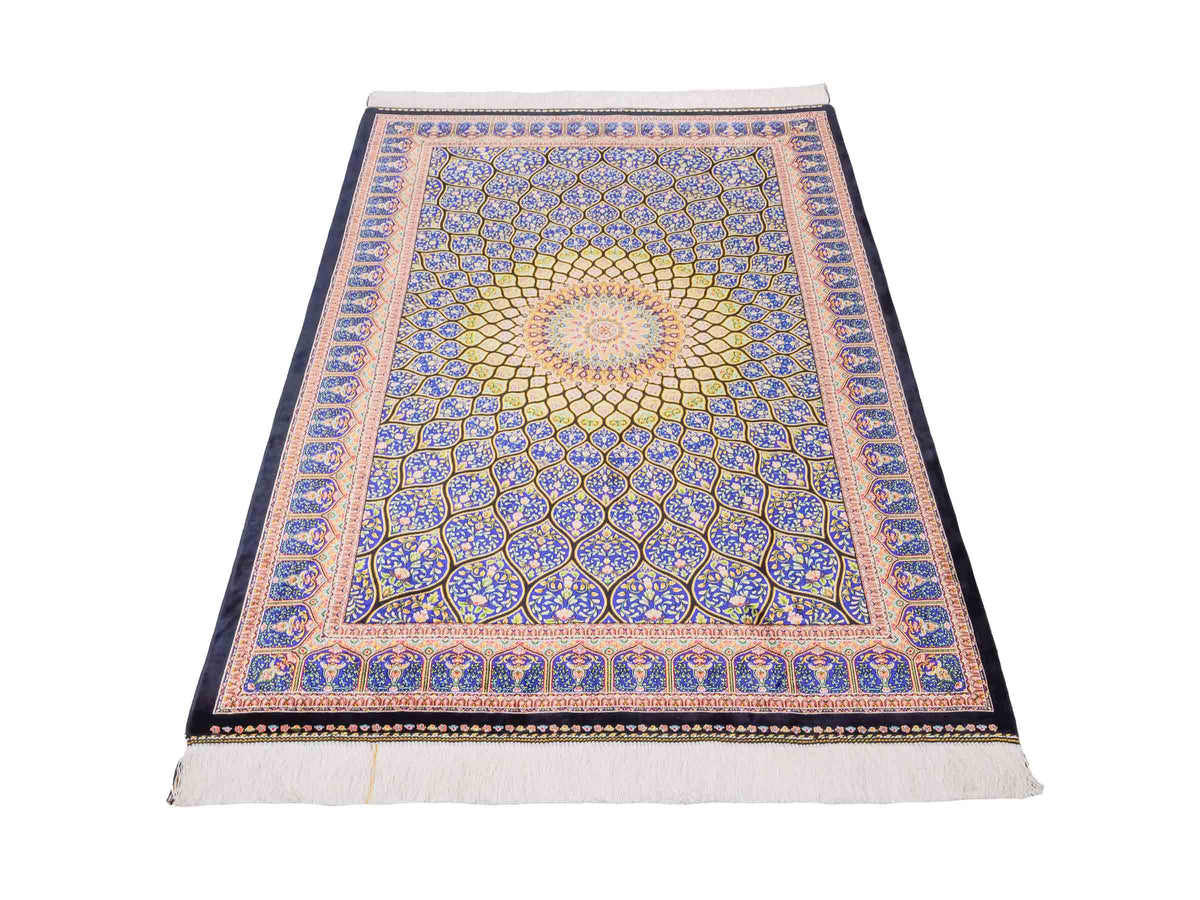 Ghom Maschinenteppich "Manuchehr" 150 x 100 cm, mit Medaillon, aus pflanzlicher Seide (Viskose), Schwarz/Blau/Gold. Teppichnummer: V56BD150H. Persian Luxury Collection by Khademi. Made in Iran / Persia – Vertrieb durch JUPITER Intl.