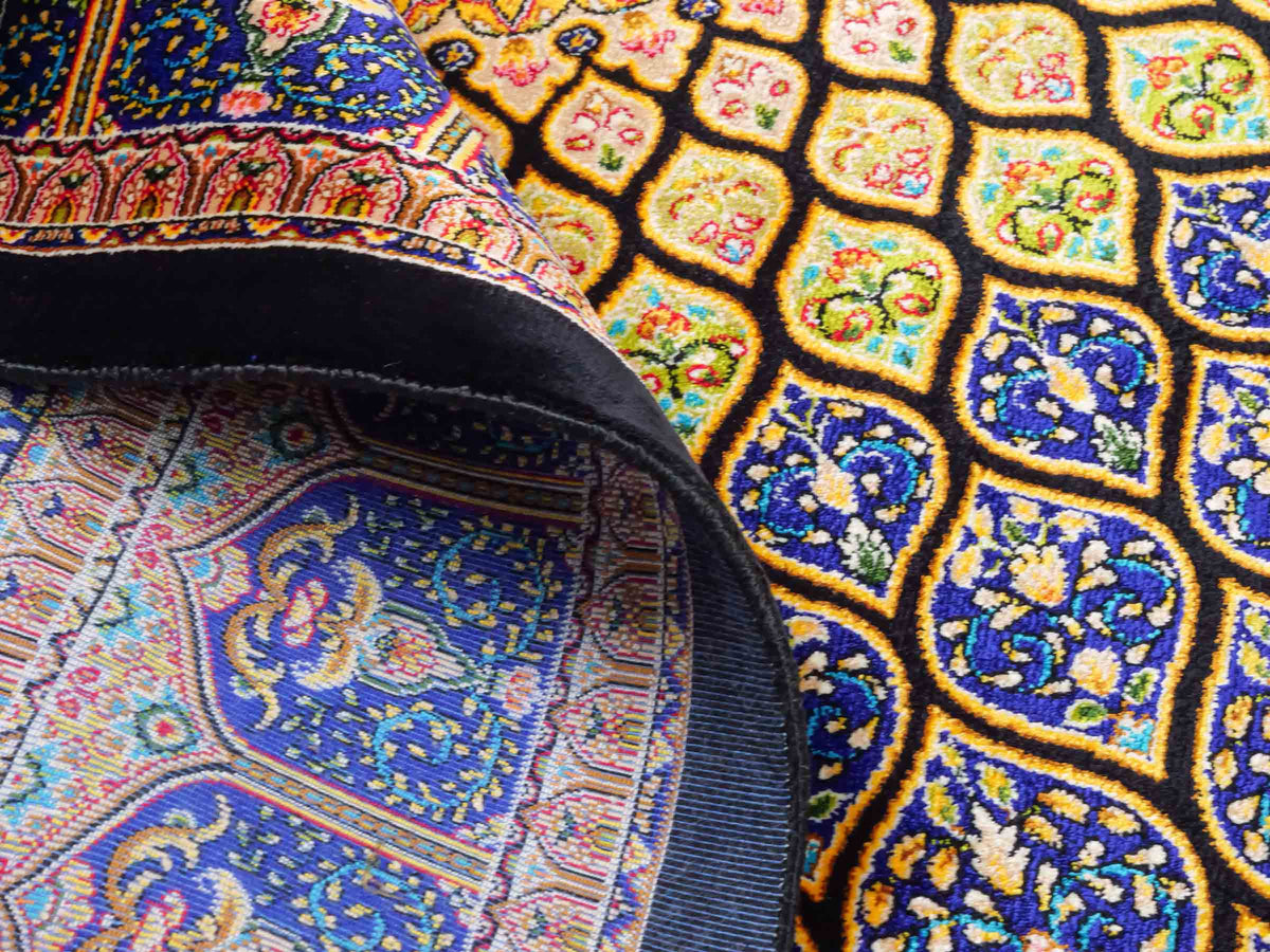 Ghom Maschinenteppich "Manuchehr" 150 x 100 cm, mit Medaillon, aus pflanzlicher Seide (Viskose), Schwarz/Blau/Gold. Teppichnummer: V56BD150H. Persian Luxury Collection by Khademi. Made in Iran / Persia – Vertrieb durch JUPITER Intl.