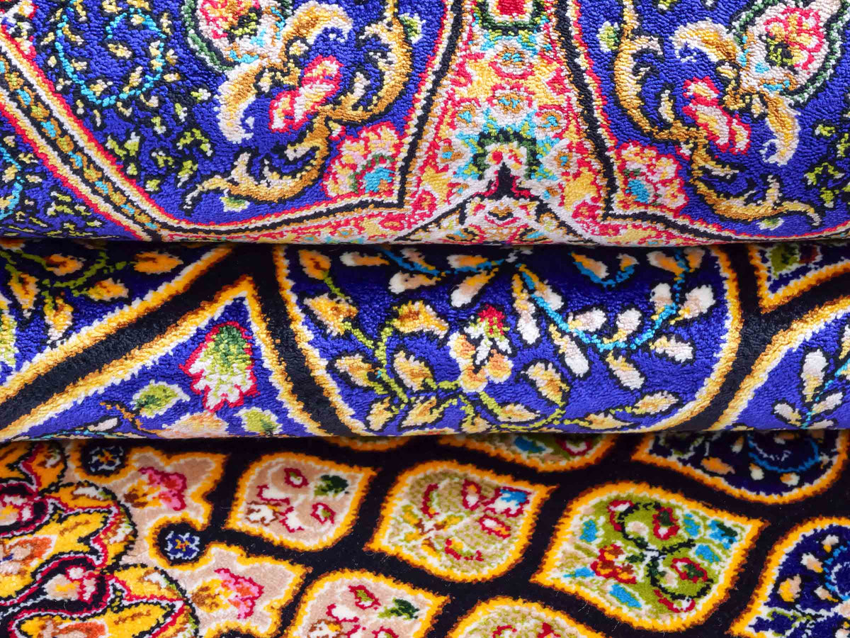 Ghom Maschinenteppich "Manuchehr" 150 x 100 cm, mit Medaillon, aus pflanzlicher Seide (Viskose), Schwarz/Blau/Gold. Teppichnummer: V56BD150H. Persian Luxury Collection by Khademi. Made in Iran / Persia – Vertrieb durch JUPITER Intl.