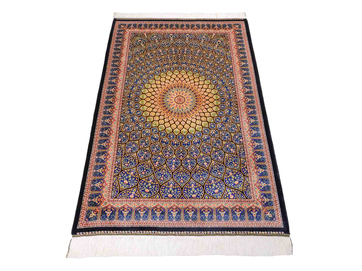 Ghom Maschinenteppich "Manuchehr" 150 x 100 cm, mit Medaillon, aus pflanzlicher Seide (Viskose), Schwarz/Blau/Gold. Teppichnummer: V56BD150H. Persian Luxury Collection by Khademi. Made in Iran / Persia – Vertrieb durch JUPITER Intl.