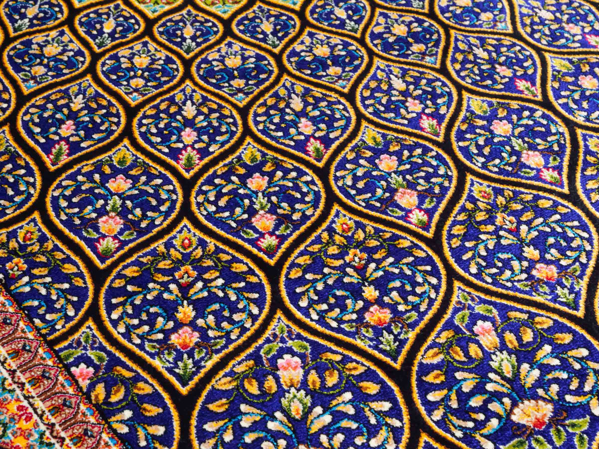 Ghom Maschinenteppich "Manuchehr" 150 x 100 cm, mit Medaillon, aus pflanzlicher Seide (Viskose), Schwarz/Blau/Gold. Teppichnummer: V56BD150H. Persian Luxury Collection by Khademi. Made in Iran / Persia – Vertrieb durch JUPITER Intl.