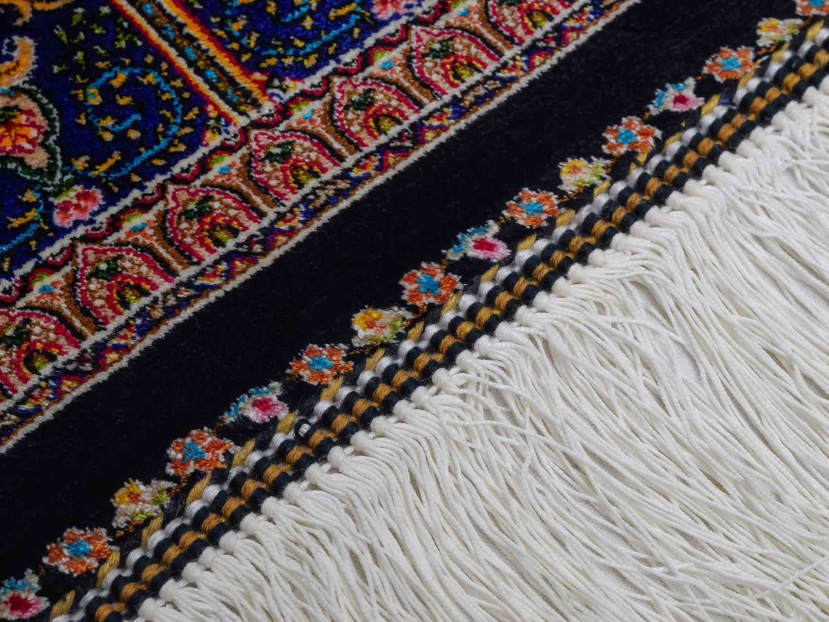 Ghom Maschinenteppich "Manuchehr" 150 x 100 cm, mit Medaillon, aus pflanzlicher Seide (Viskose), Schwarz/Blau/Gold. Teppichnummer: V56BD150H. Persian Luxury Collection by Khademi. Made in Iran / Persia – Vertrieb durch JUPITER Intl.