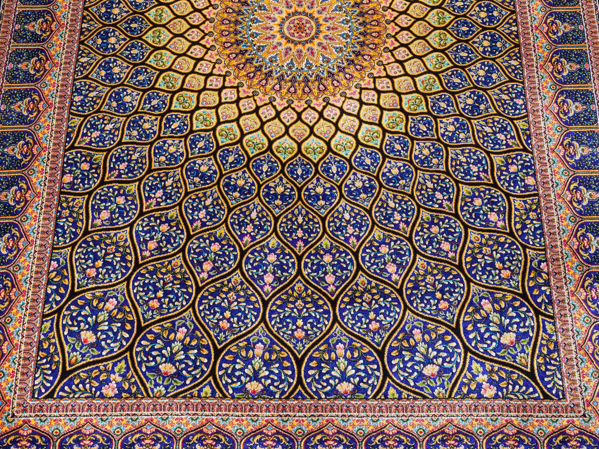 Ghom Maschinenteppich "Manuchehr" 150 x 100 cm, mit Medaillon, aus pflanzlicher Seide (Viskose), Schwarz/Blau/Gold. Teppichnummer: V56BD150H. Persian Luxury Collection by Khademi. Made in Iran / Persia – Vertrieb durch JUPITER Intl.
