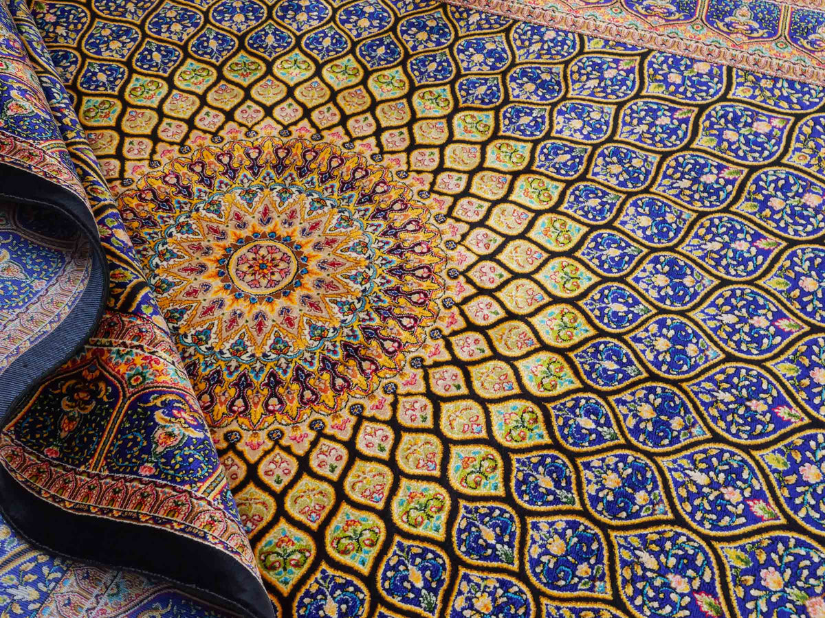 Ghom Maschinenteppich "Manuchehr" 150 x 100 cm, mit Medaillon, aus pflanzlicher Seide (Viskose), Schwarz/Blau/Gold. Teppichnummer: V56BD150H. Persian Luxury Collection by Khademi. Made in Iran / Persia – Vertrieb durch JUPITER Intl.