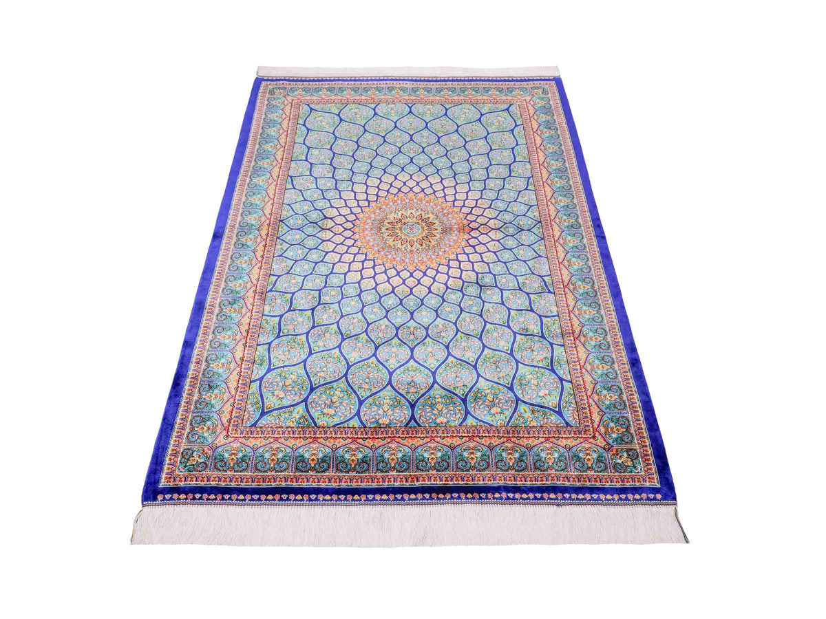 Ghom Maschinenteppich "Manuchehr" 150 x 100 cm, mit Medaillon, aus pflanzlicher Seide (Viskose), Dunkelblau/Blau. Teppichnummer: V56DB150H. Persian Luxury Collection by Khademi. Made in Iran / Persia – Vertrieb durch JUPITER Intl.