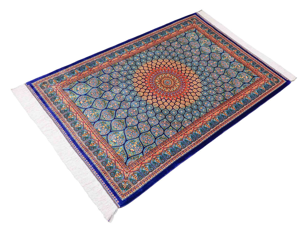 Ghom Maschinenteppich "Manuchehr" 150 x 100 cm, mit Medaillon, aus pflanzlicher Seide (Viskose), Dunkelblau/Blau. Teppichnummer: V56DB150H. Persian Luxury Collection by Khademi. Made in Iran / Persia – Vertrieb durch JUPITER Intl.