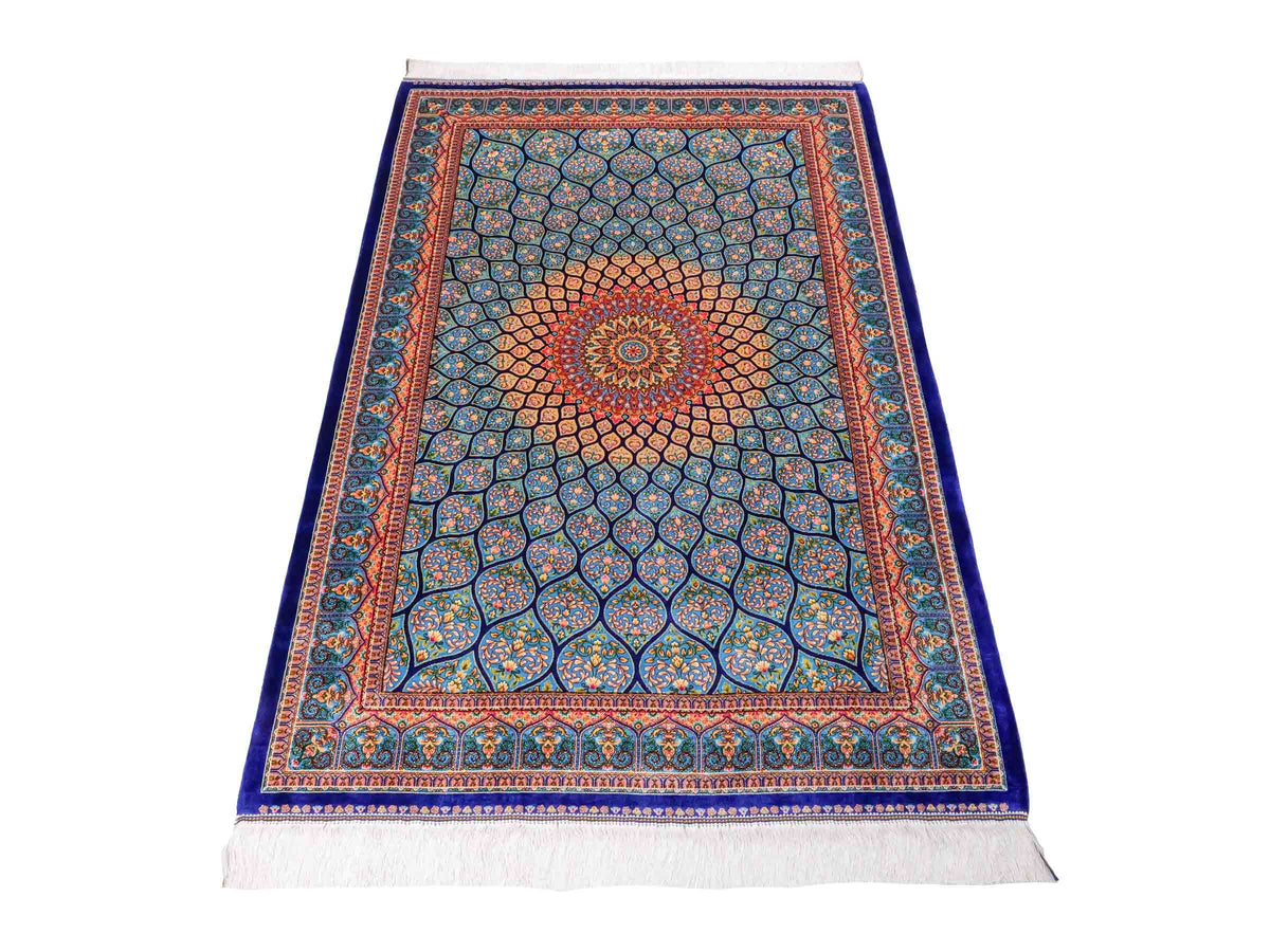 Ghom Maschinenteppich "Manuchehr" 150 x 100 cm, mit Medaillon, aus pflanzlicher Seide (Viskose), Dunkelblau/Blau. Teppichnummer: V56DB150H. Persian Luxury Collection by Khademi. Made in Iran / Persia – Vertrieb durch JUPITER Intl.