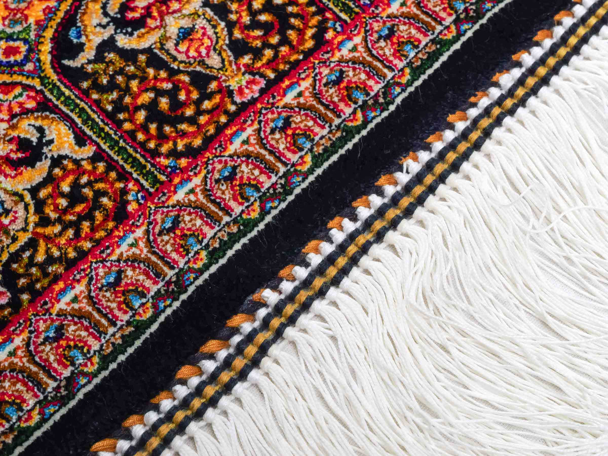Ghom Maschinenteppich "Manuchehr" 150 x 100 cm, mit Medaillon, aus pflanzlicher Seide (Viskose), Schwarz/Gold. Teppichnummer: V56BG150H. Persian Luxury Collection by Khademi. Made in Iran / Persia – Vertrieb durch JUPITER Intl.
