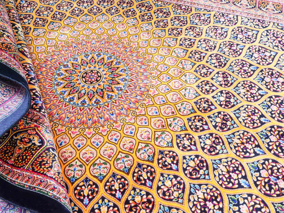 Ghom Maschinenteppich "Manuchehr" 150 x 100 cm, mit Medaillon, aus pflanzlicher Seide (Viskose), Schwarz/Gold. Teppichnummer: V56BG150H. Persian Luxury Collection by Khademi. Made in Iran / Persia – Vertrieb durch JUPITER Intl.