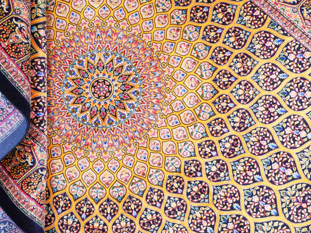 Ghom Maschinenteppich "Manuchehr" 150 x 100 cm, mit Medaillon, aus pflanzlicher Seide (Viskose), Schwarz/Gold. Teppichnummer: V56BG150H. Persian Luxury Collection by Khademi. Made in Iran / Persia – Vertrieb durch JUPITER Intl.