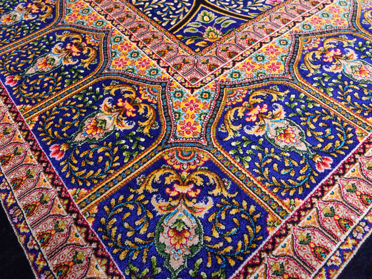 Ghom Maschinenteppich "Manuchehr" 225 x 150 cm, mit Medaillon, aus pflanzlicher Seide (Viskose), Schwarz/Blau/Gold. Teppichnummer: V56BD338H. Persian Luxury Collection by Khademi. Made in Iran / Persia – Vertrieb durch JUPITER Intl.