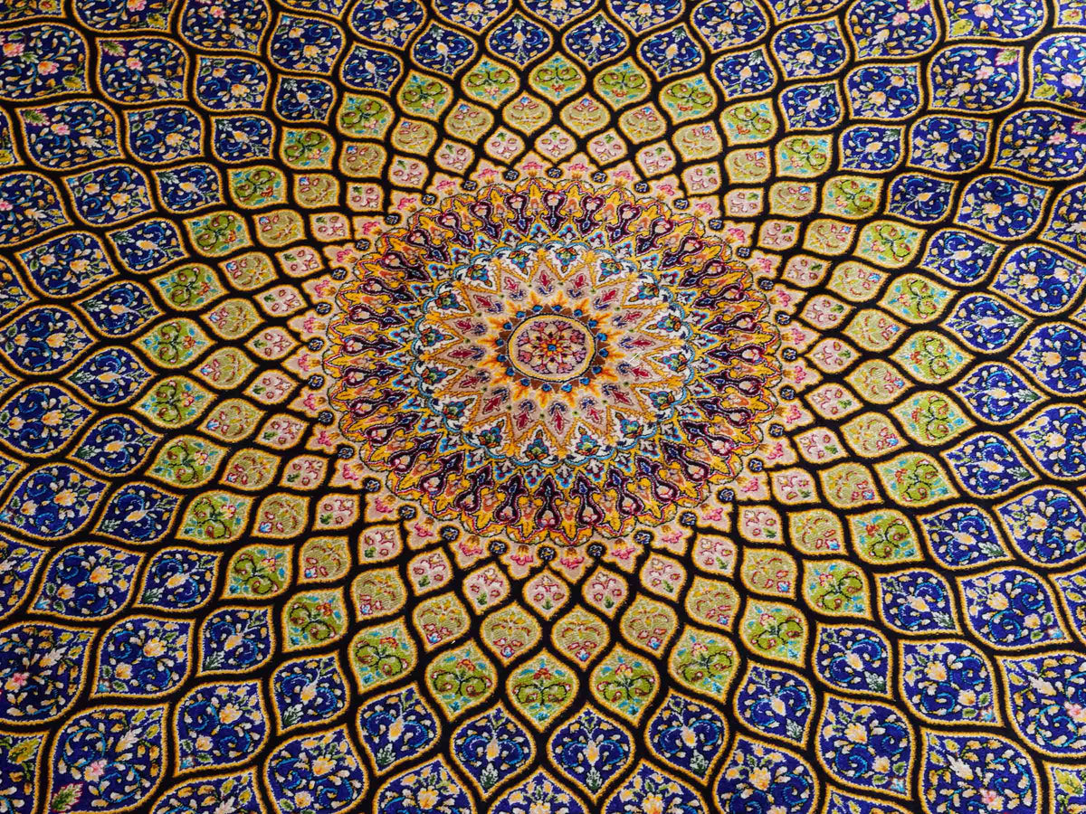 Ghom Maschinenteppich "Manuchehr" 225 x 150 cm, mit Medaillon, aus pflanzlicher Seide (Viskose), Schwarz/Blau/Gold. Teppichnummer: V56BD338H. Persian Luxury Collection by Khademi. Made in Iran / Persia – Vertrieb durch JUPITER Intl.