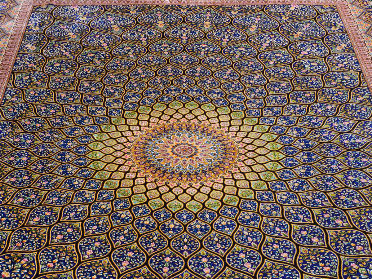 Ghom Maschinenteppich "Manuchehr" 225 x 150 cm, mit Medaillon, aus pflanzlicher Seide (Viskose), Schwarz/Blau/Gold. Teppichnummer: V56BD338H. Persian Luxury Collection by Khademi. Made in Iran / Persia – Vertrieb durch JUPITER Intl.