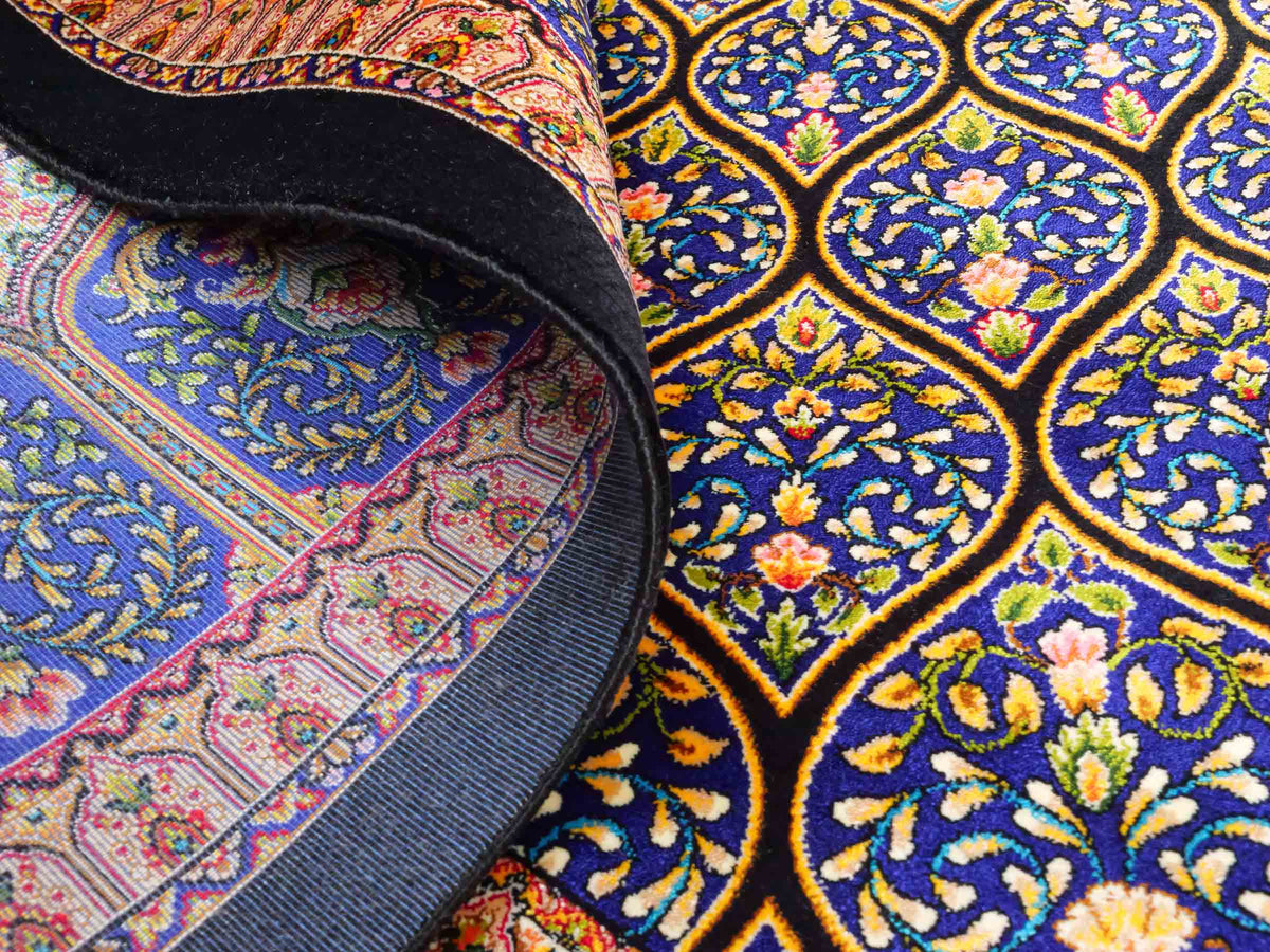 Ghom Maschinenteppich "Manuchehr" 225 x 150 cm, mit Medaillon, aus pflanzlicher Seide (Viskose), Schwarz/Blau/Gold. Teppichnummer: V56BD338H. Persian Luxury Collection by Khademi. Made in Iran / Persia – Vertrieb durch JUPITER Intl.