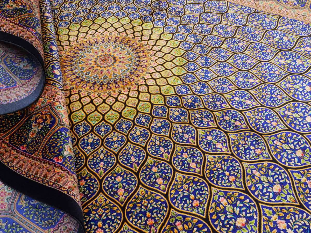 Ghom Maschinenteppich "Manuchehr" 225 x 150 cm, mit Medaillon, aus pflanzlicher Seide (Viskose), Schwarz/Blau/Gold. Teppichnummer: V56BD338H. Persian Luxury Collection by Khademi. Made in Iran / Persia – Vertrieb durch JUPITER Intl.