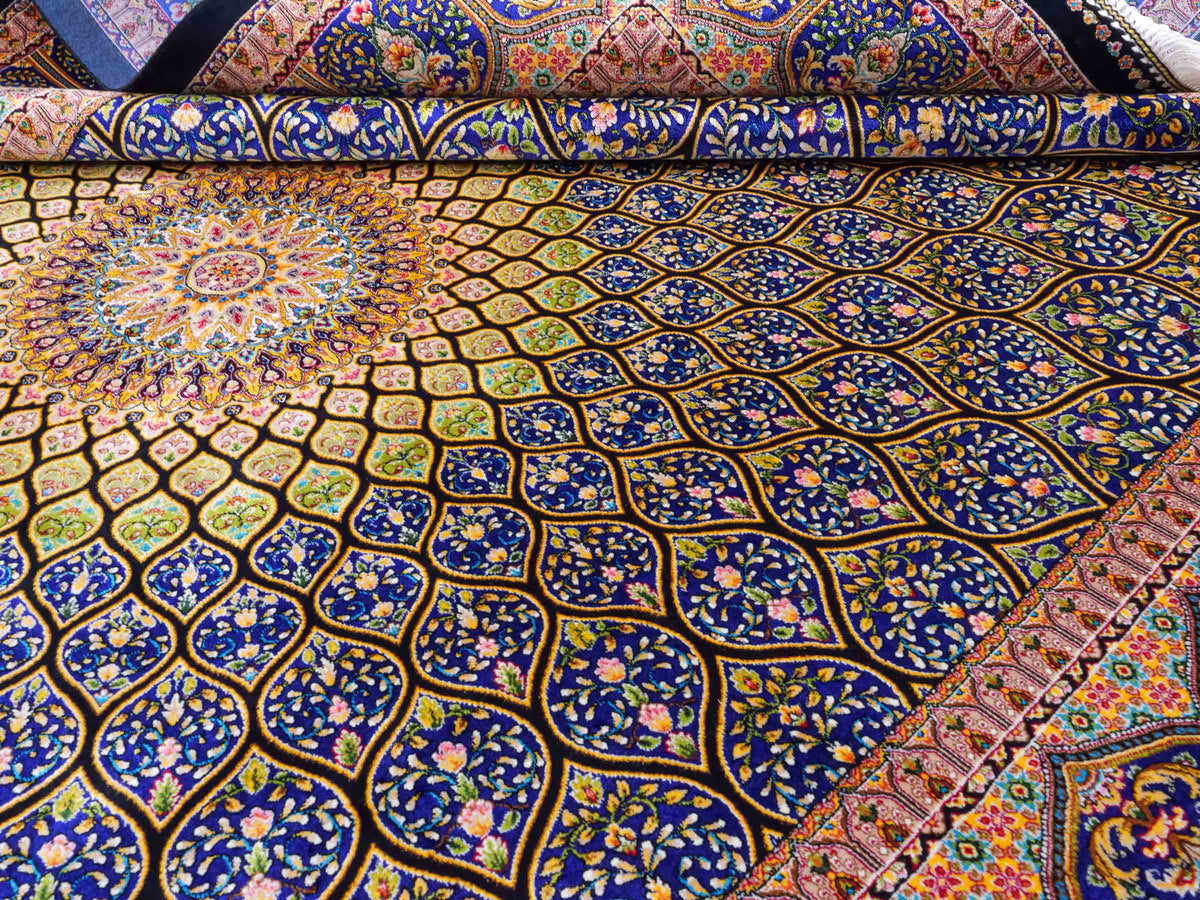 Ghom Maschinenteppich "Manuchehr" 225 x 150 cm, mit Medaillon, aus pflanzlicher Seide (Viskose), Schwarz/Blau/Gold. Teppichnummer: V56BD338H. Persian Luxury Collection by Khademi. Made in Iran / Persia – Vertrieb durch JUPITER Intl.