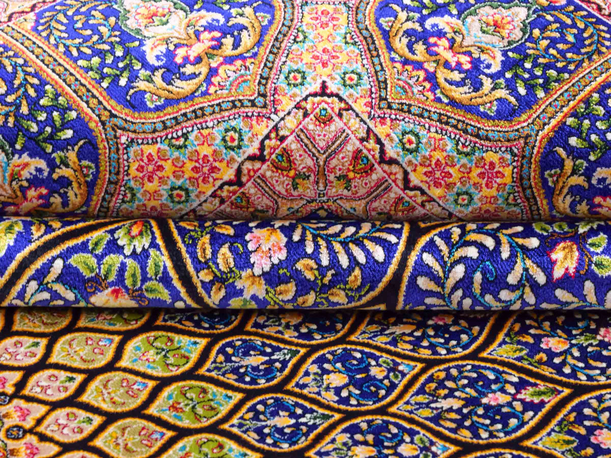 Ghom Maschinenteppich "Manuchehr" 225 x 150 cm, mit Medaillon, aus pflanzlicher Seide (Viskose), Schwarz/Blau/Gold. Teppichnummer: V56BD338H. Persian Luxury Collection by Khademi. Made in Iran / Persia – Vertrieb durch JUPITER Intl.