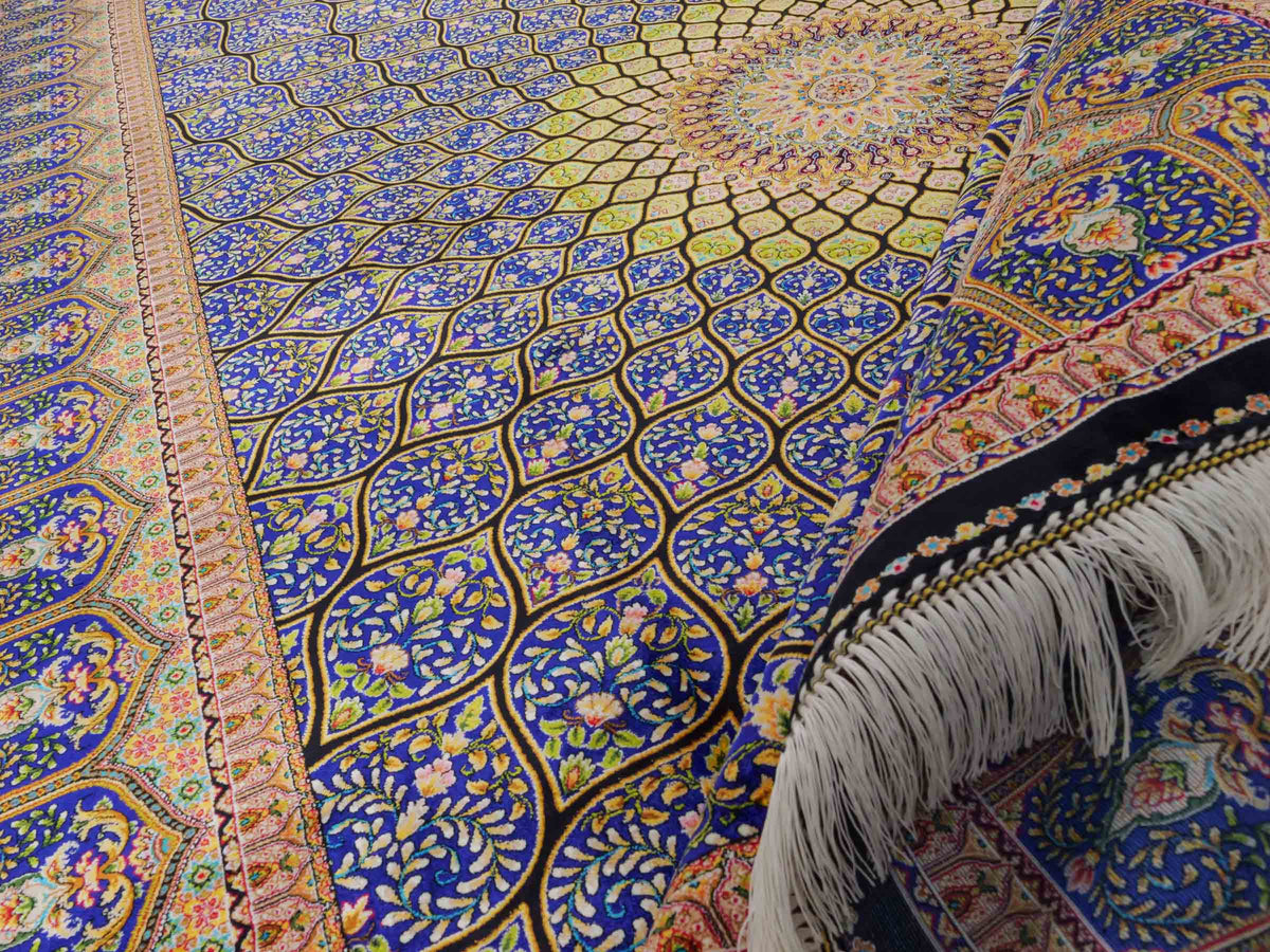 Ghom Maschinenteppich "Manuchehr" 225 x 150 cm, mit Medaillon, aus pflanzlicher Seide (Viskose), Schwarz/Blau/Gold. Teppichnummer: V56BD338H. Persian Luxury Collection by Khademi. Made in Iran / Persia – Vertrieb durch JUPITER Intl.