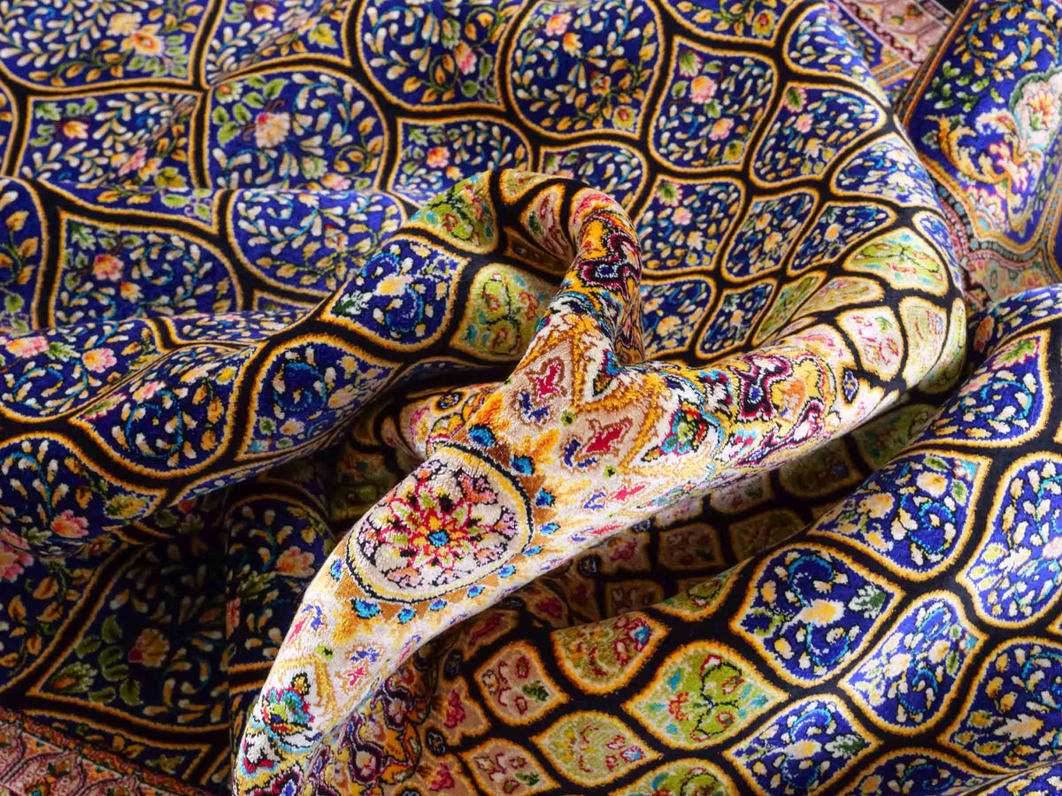Ghom Maschinenteppich "Manuchehr" 225 x 150 cm, mit Medaillon, aus pflanzlicher Seide (Viskose), Schwarz/Blau/Gold. Teppichnummer: V56BD338H. Persian Luxury Collection by Khademi. Made in Iran / Persia – Vertrieb durch JUPITER Intl.