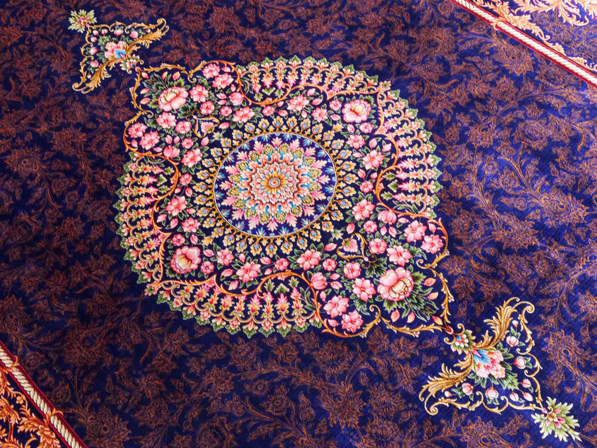 Ghom Maschinenteppich "Piruz" 225 x 150 cm, mit Medaillon, aus pflanzlicher Seide (Viskose), Marineblau/Orange/Gold. Teppichnummer: V69NY338H. Persian Luxury Collection by Khademi. Made in Iran / Persia – Vertrieb durch JUPITER Intl.