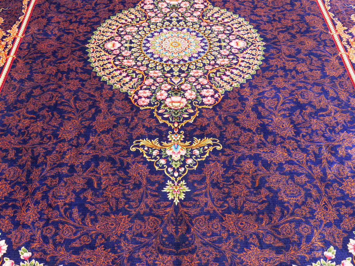 Ghom Maschinenteppich "Piruz" 225 x 150 cm, mit Medaillon, aus pflanzlicher Seide (Viskose), Marineblau/Orange/Gold. Teppichnummer: V69NY338H. Persian Luxury Collection by Khademi. Made in Iran / Persia – Vertrieb durch JUPITER Intl.