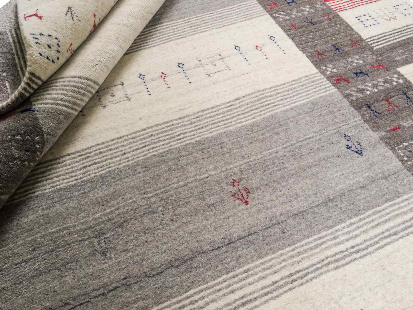 Moderner, Handloom Lori Gabbeh Orientteppich von Khademi aus Wolle mit Bambusseide, cremeweiß, grau, blau, rot. Nomaden-Design. Produziert in Indien. Größe: 239x168cm. Teppichnummer: KB4-1806. Verkauf durch Jupiter Intl.