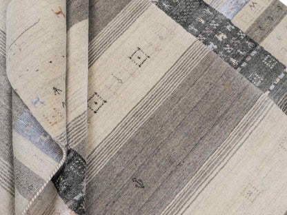 Moderner, Handloom Lori Gabbeh Orientteppich von Khademi aus Wolle mit Bambusseide, cremeweiß, grau, blau, braun. Nomaden-Design. Produziert in Indien. Größe: 241x172cm. Teppichnummer: KB4-1805. Verkauf durch Jupiter Intl.