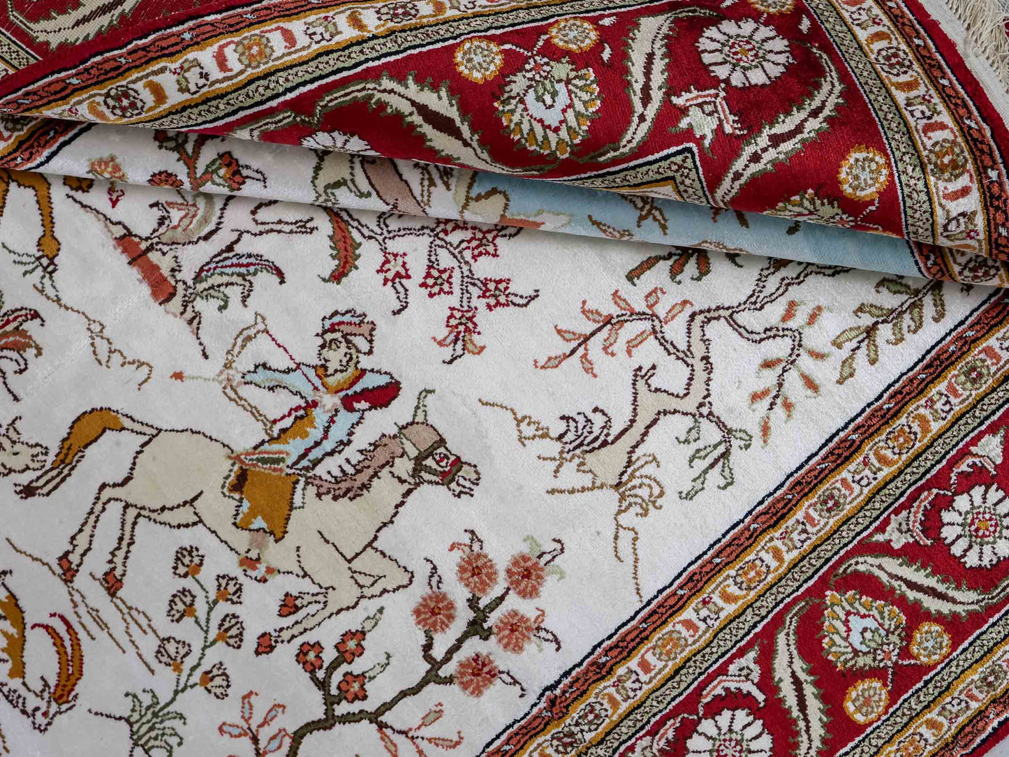 Feiner, handgeknüpfter Art Ghom aus Kunstseide. Ursprung China. Größe: 184 x 120 cm. Hauptfarben: Weiß, Creme, Rot. Vertrieb durch JUPITER Intl.