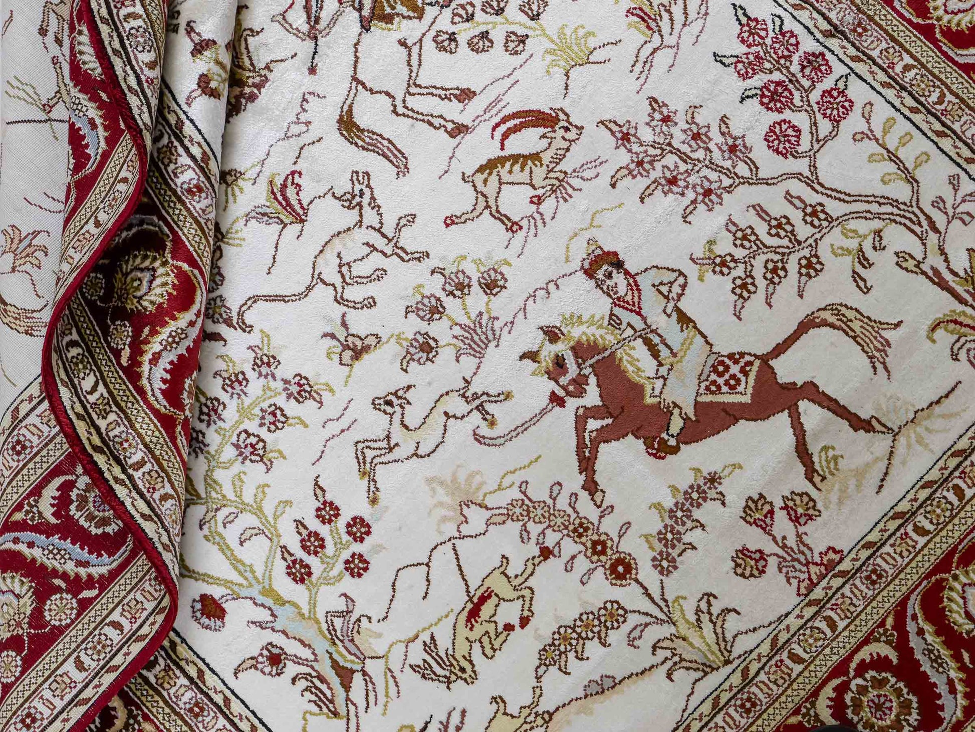 Feiner, handgeknüpfter Art Ghom aus Kunstseide. Ursprung China. Größe: 185 x 124 cm. Hauptfarben: Weiß, Creme, Rot. Vertrieb durch JUPITER Intl.